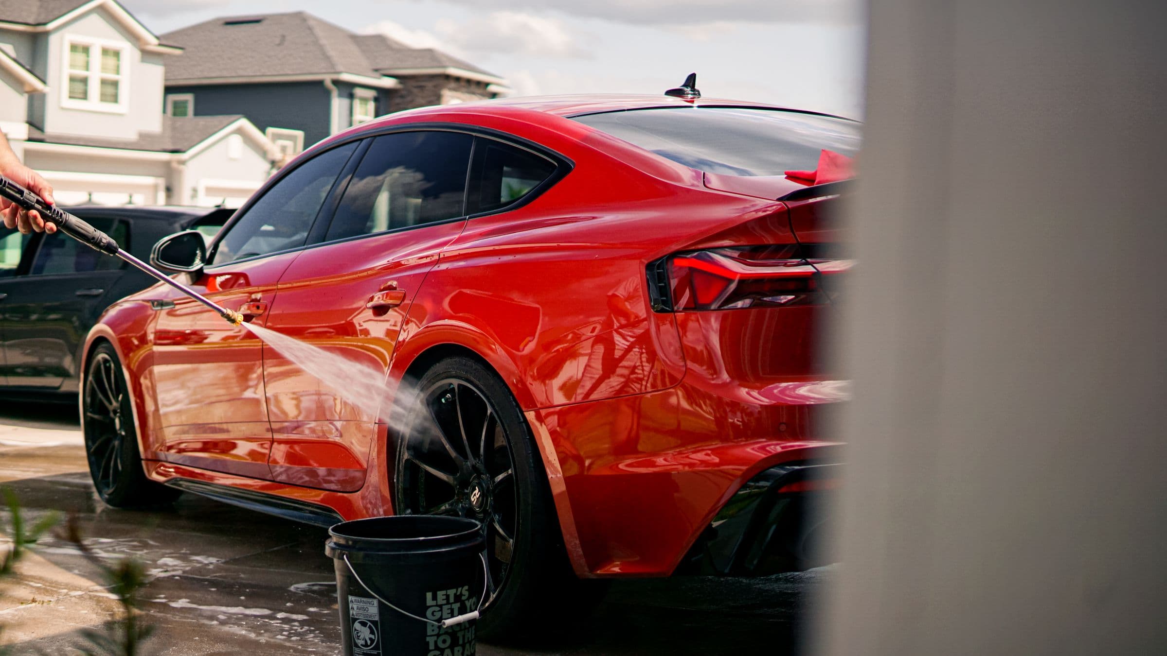 Detailer working on an SUV in a suburban South Jordan driveway with the Oquirrh mountains behind